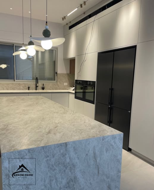 Kitchen design with stone waterfall island and black appliances