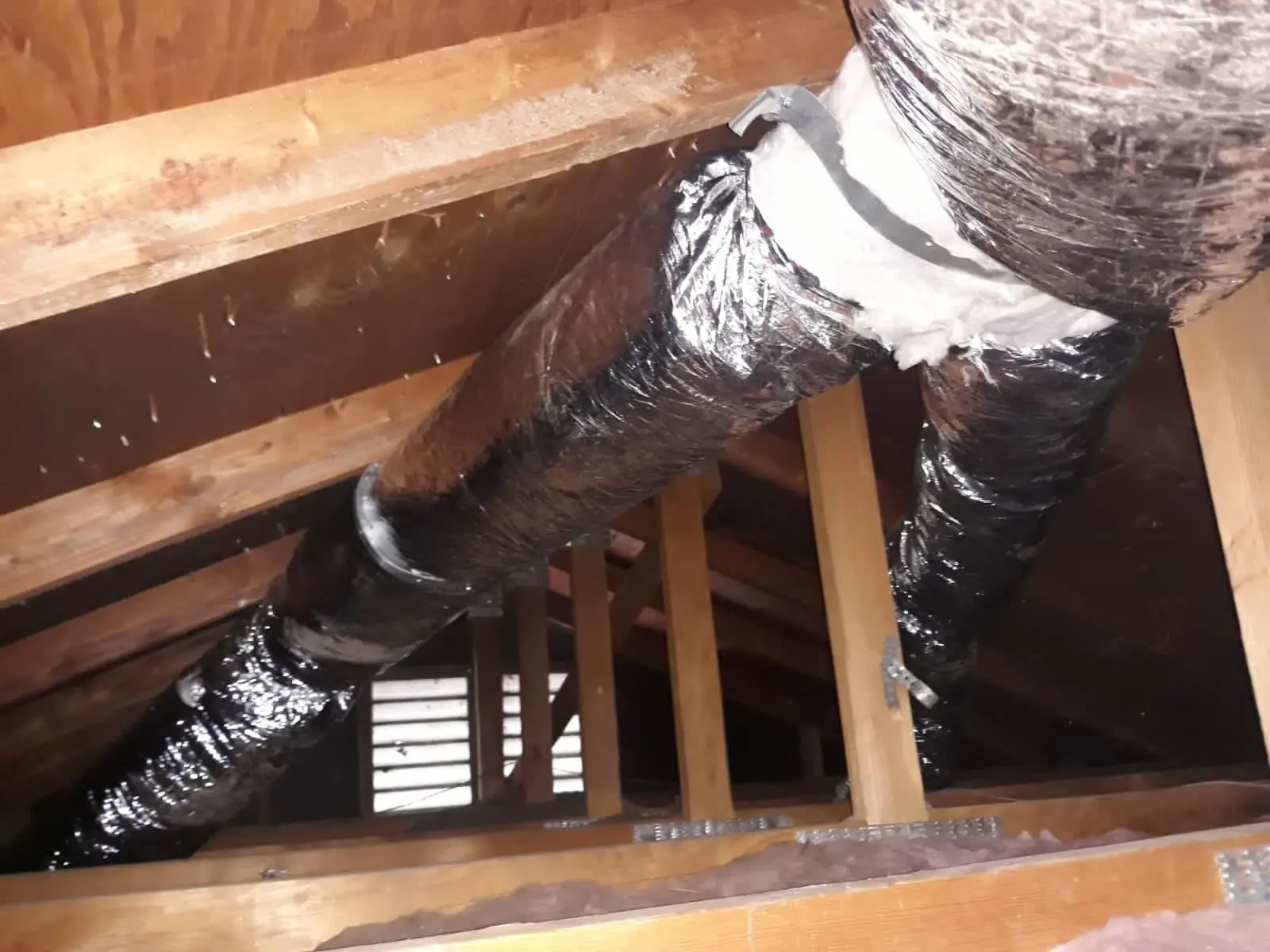 Insulated duct runs strapped in an attic