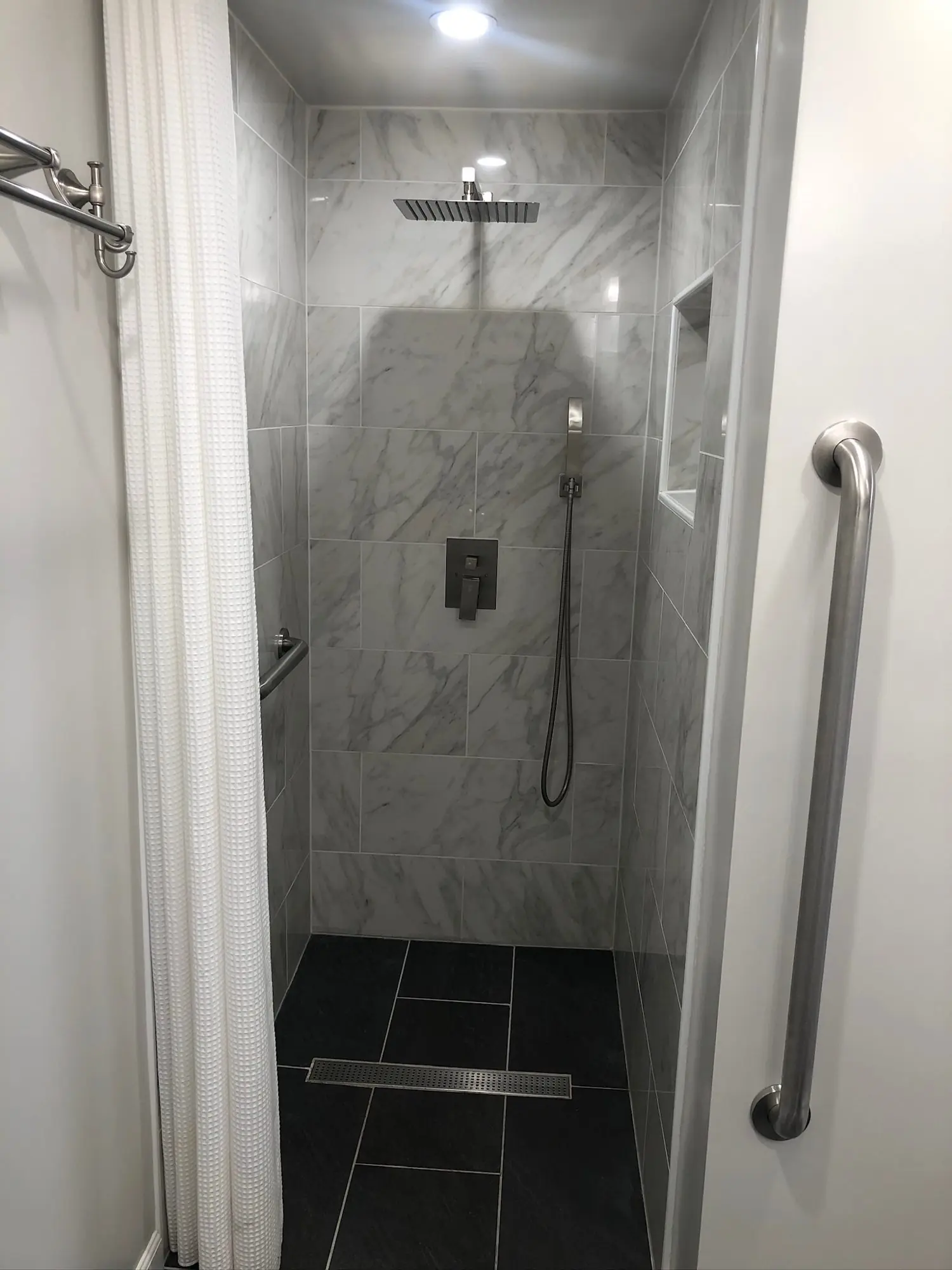 Curbless walk-in shower with linear drain and grab bars