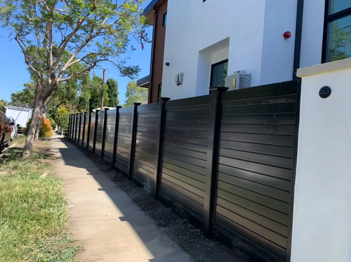 Black horizontal vinyl privacy fence along a sidewalk