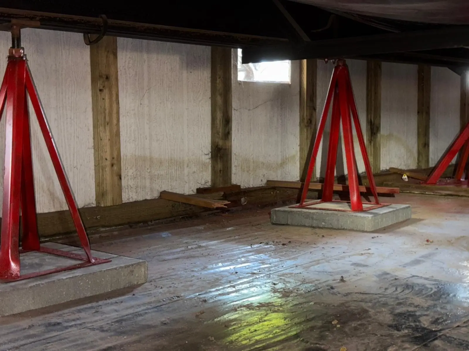 Shoring stands on pads under a house during foundation replacement