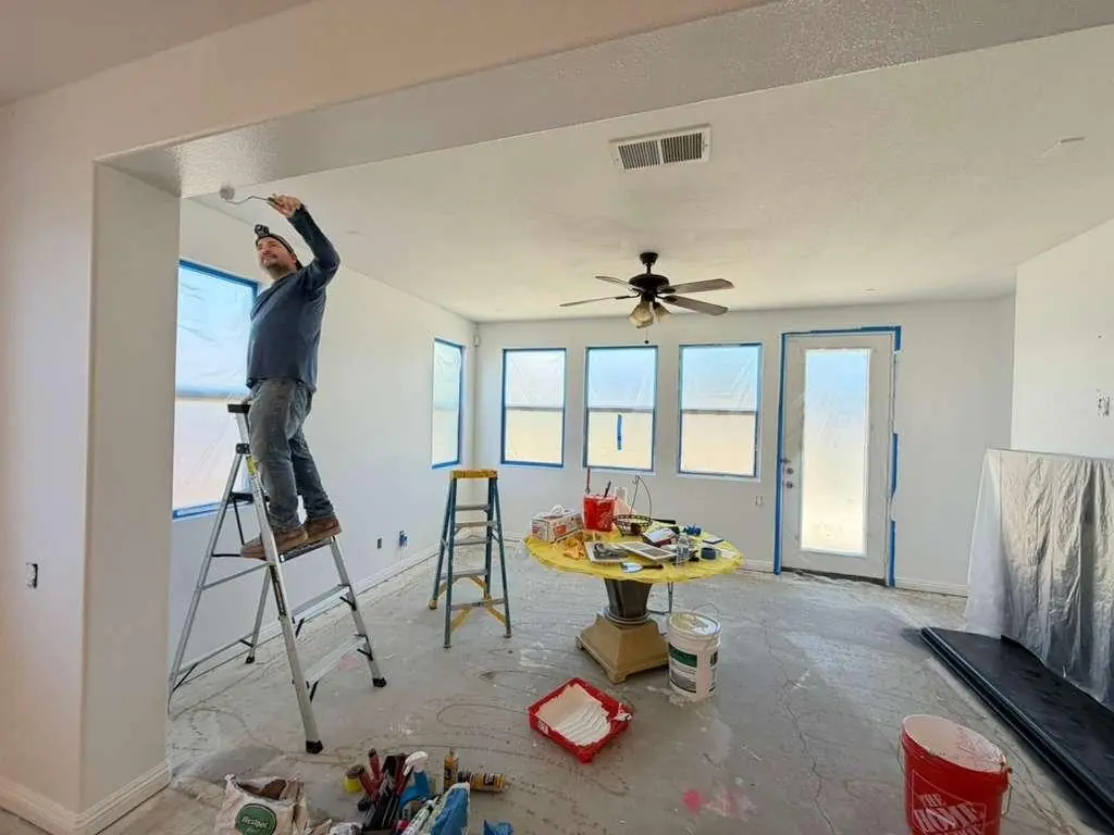 Painter rolling a ceiling with windows and floors protected