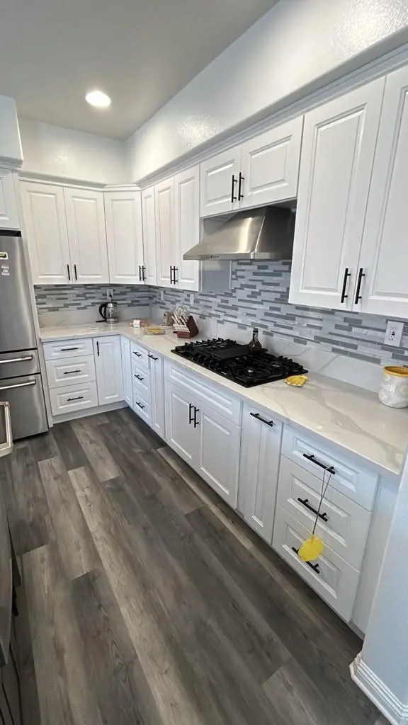 White raised-panel cabinets with gas cooktop and mosaic backsplash