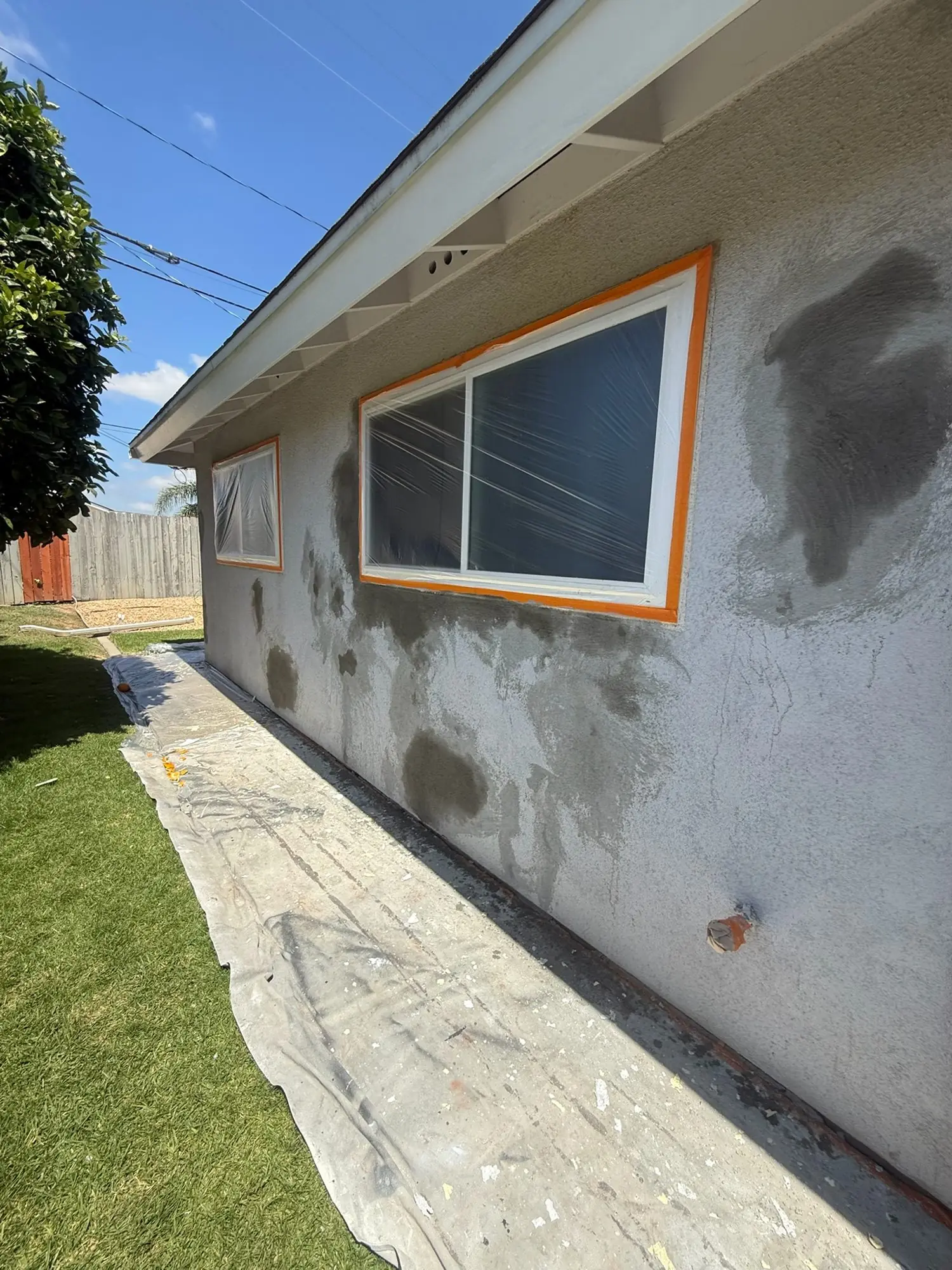 Stucco patched and windows masked before exterior painting