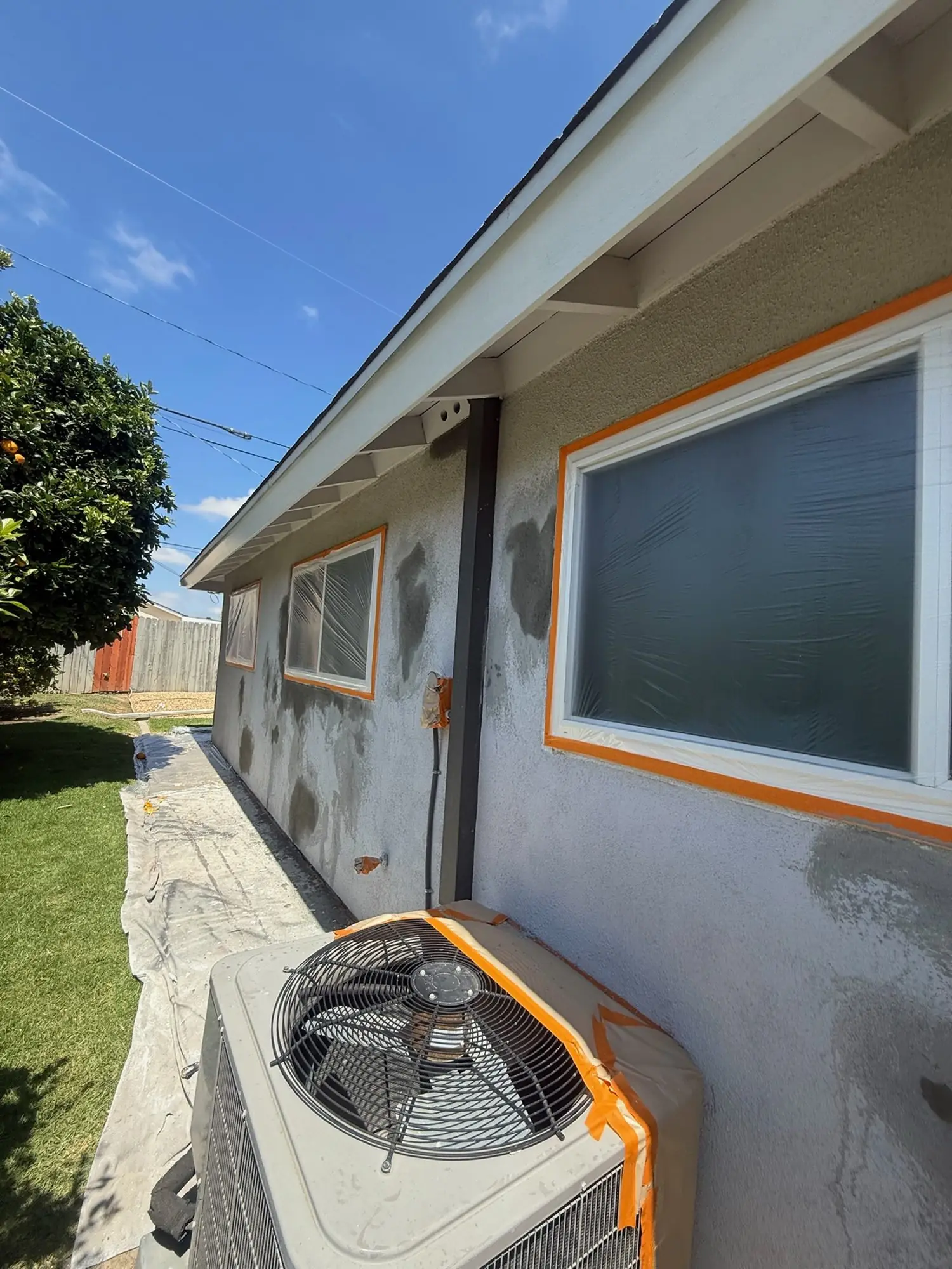AC unit and windows masked, stucco patched before painting