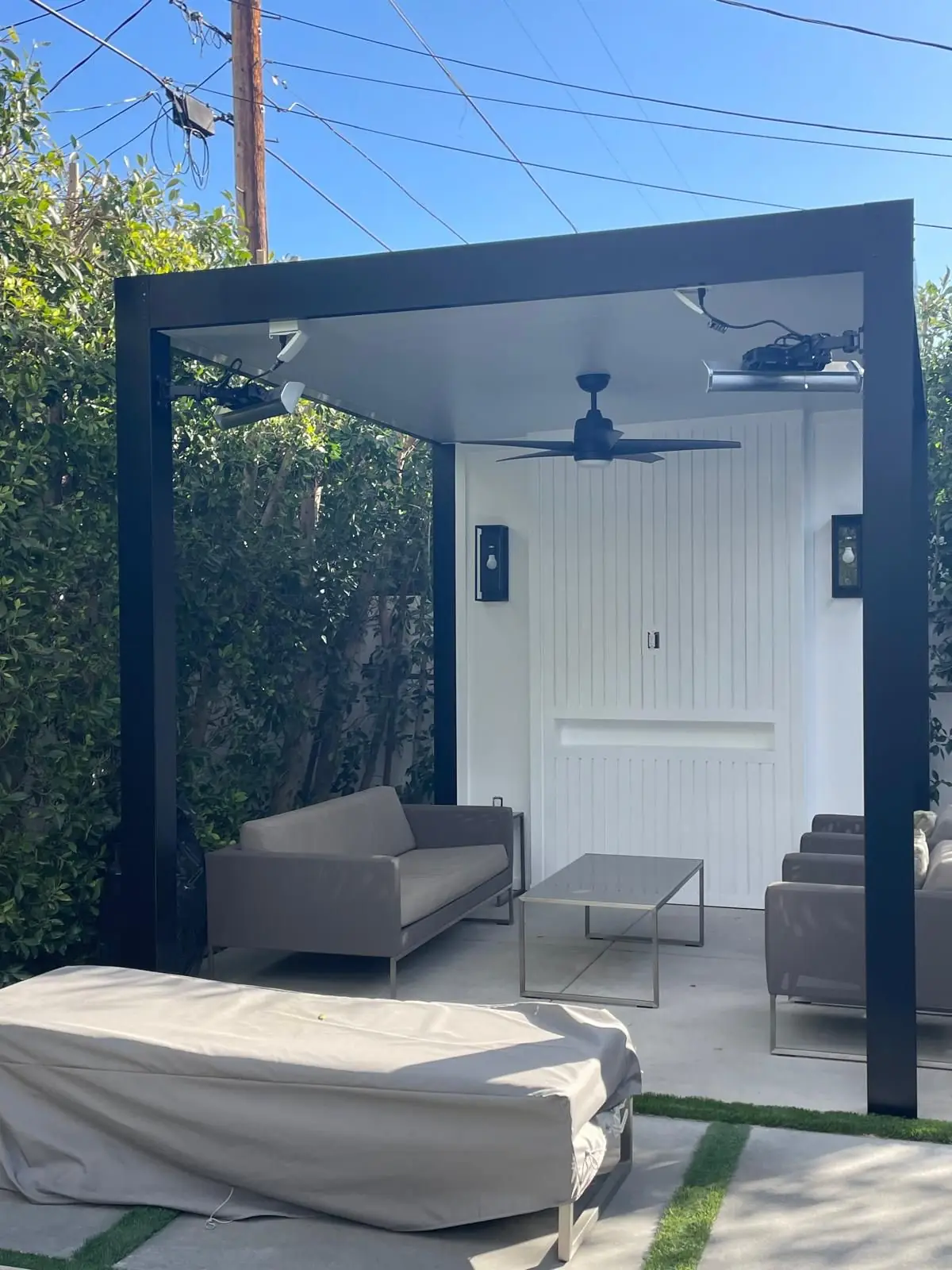 Modern black patio cover with ceiling fan, heaters and lounge seating