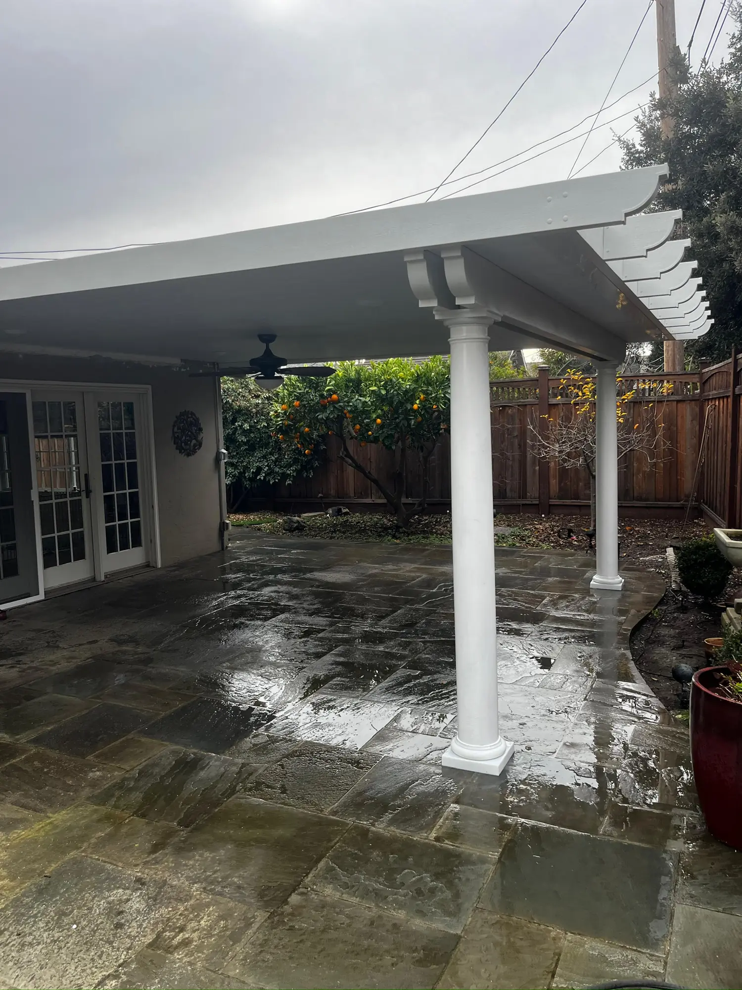 White patio cover with round columns and decorative rafter tails