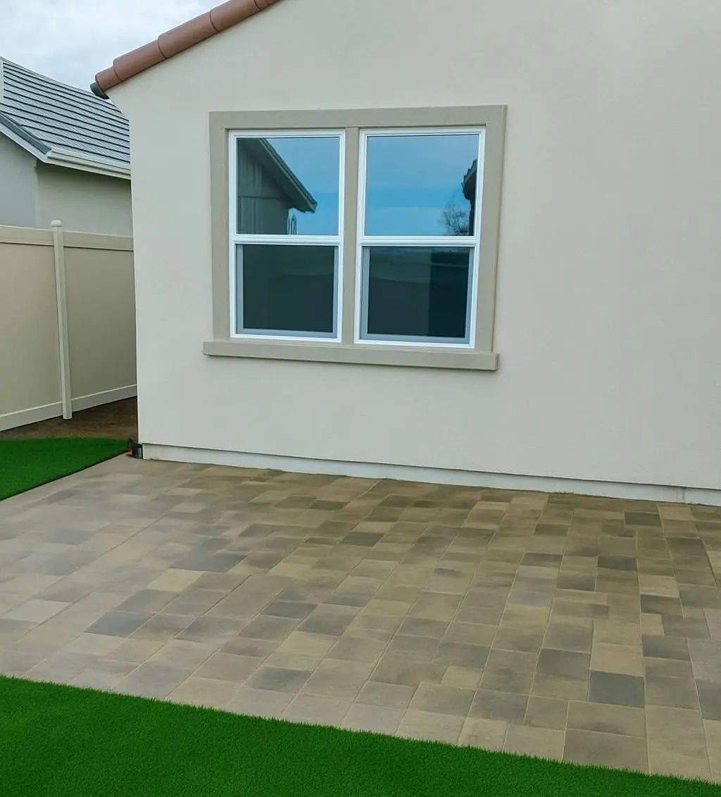 Blend paver patio meeting artificial turf beside the house