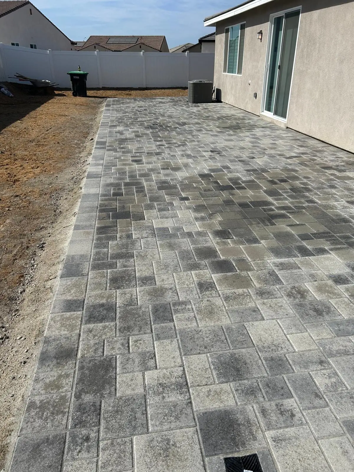 Long backyard paver patio along the house