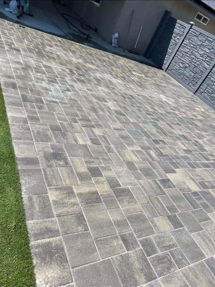 Finished paver driveway next to artificial turf
