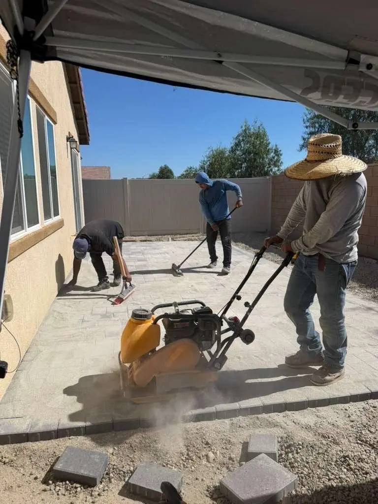 Crew compacting and sanding a new paver patio
